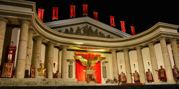 Cenário do espetáculo da Paixão de Cristo em Nova Jerusalém, Pernambuco, com arquitetura romana, colunas brancas e estátuas douradas.