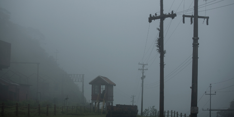Neblina densa envolve a paisagem de Paranapiacaba, obscurecendo parcialmente construções e postes de energia.