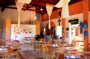 Foto do interior do Brotas Zen, um restaurante com decoração que remete à natureza e à cultura oriental. O espaço é iluminado com luz suave e decorado com bambus, pedras e plantas. As mesas de madeira estão dispostas de forma aconchegante, criando um ambiente relaxante e convidativo.
